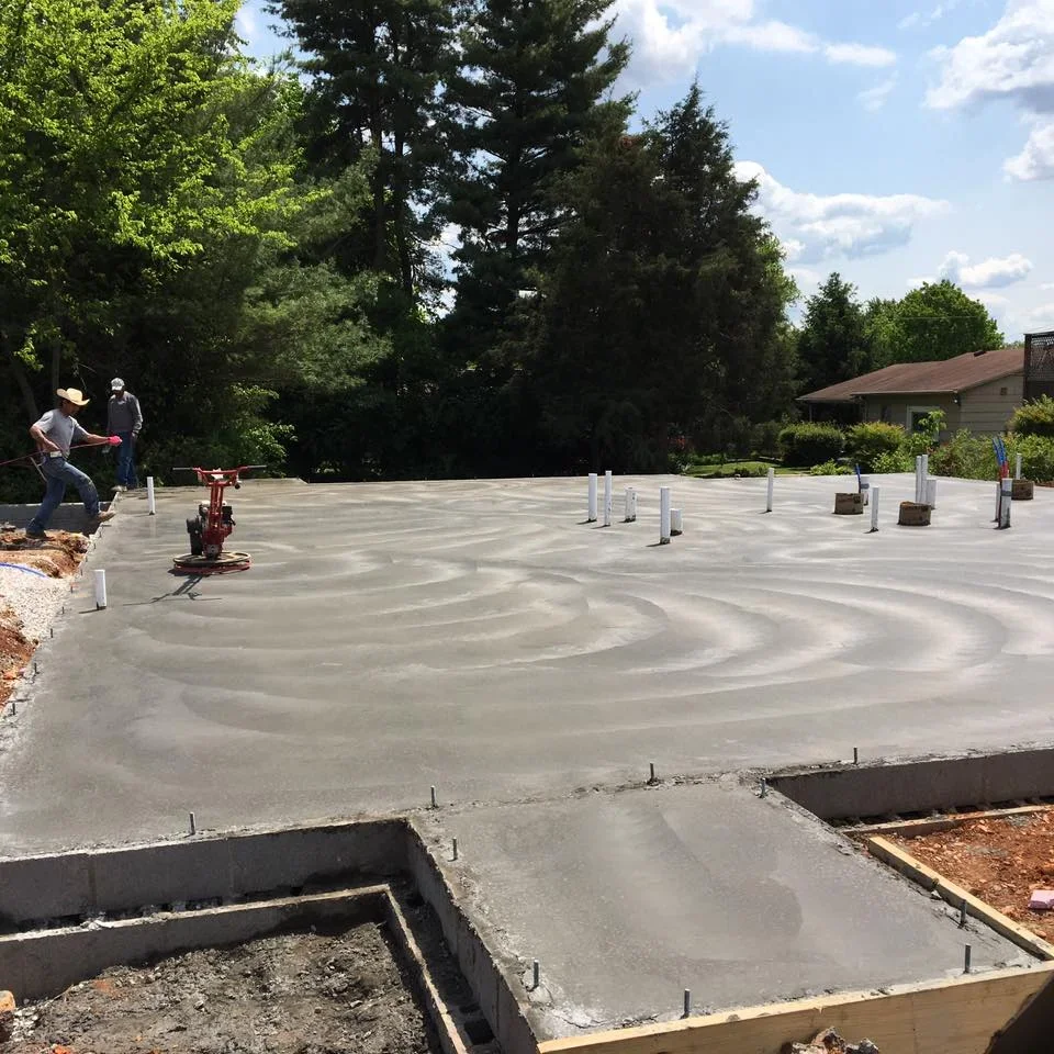 Freshly finished concrete pad with broom texture and post footings in residential setting