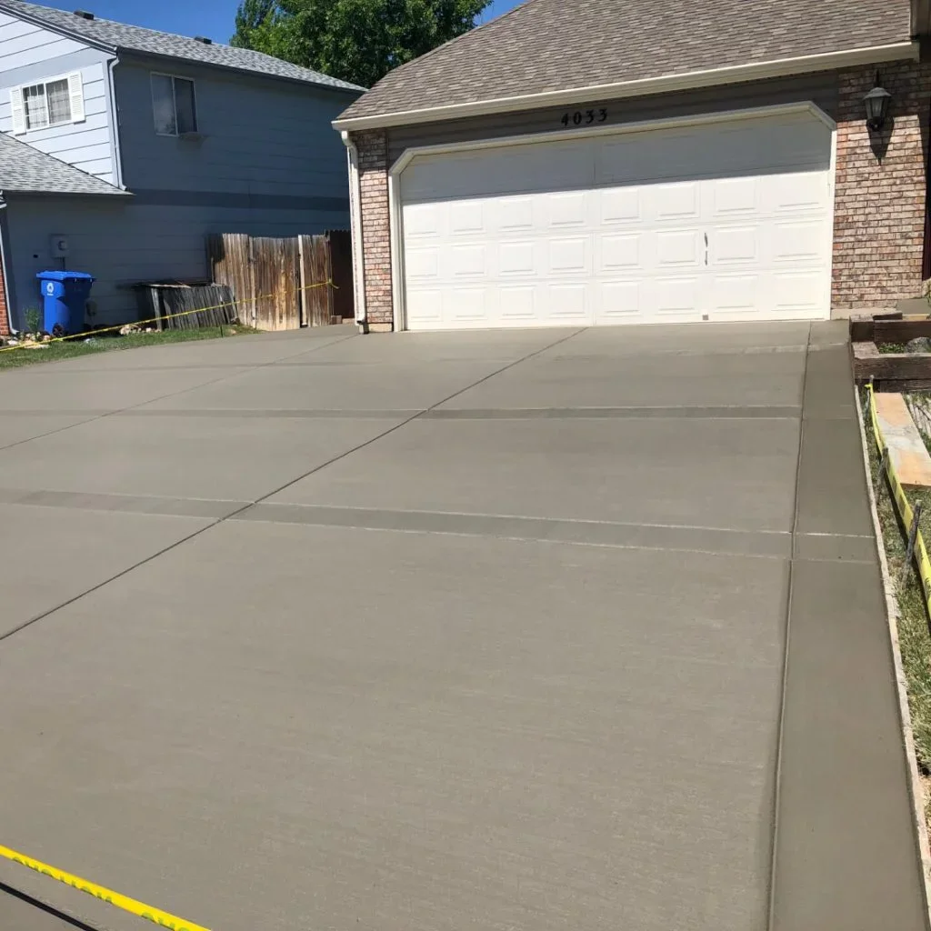 Newly poured concrete driveway with control joints and white garage door
