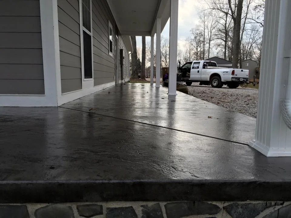 Finished concrete porch and driveway with white columns and gravel driveway