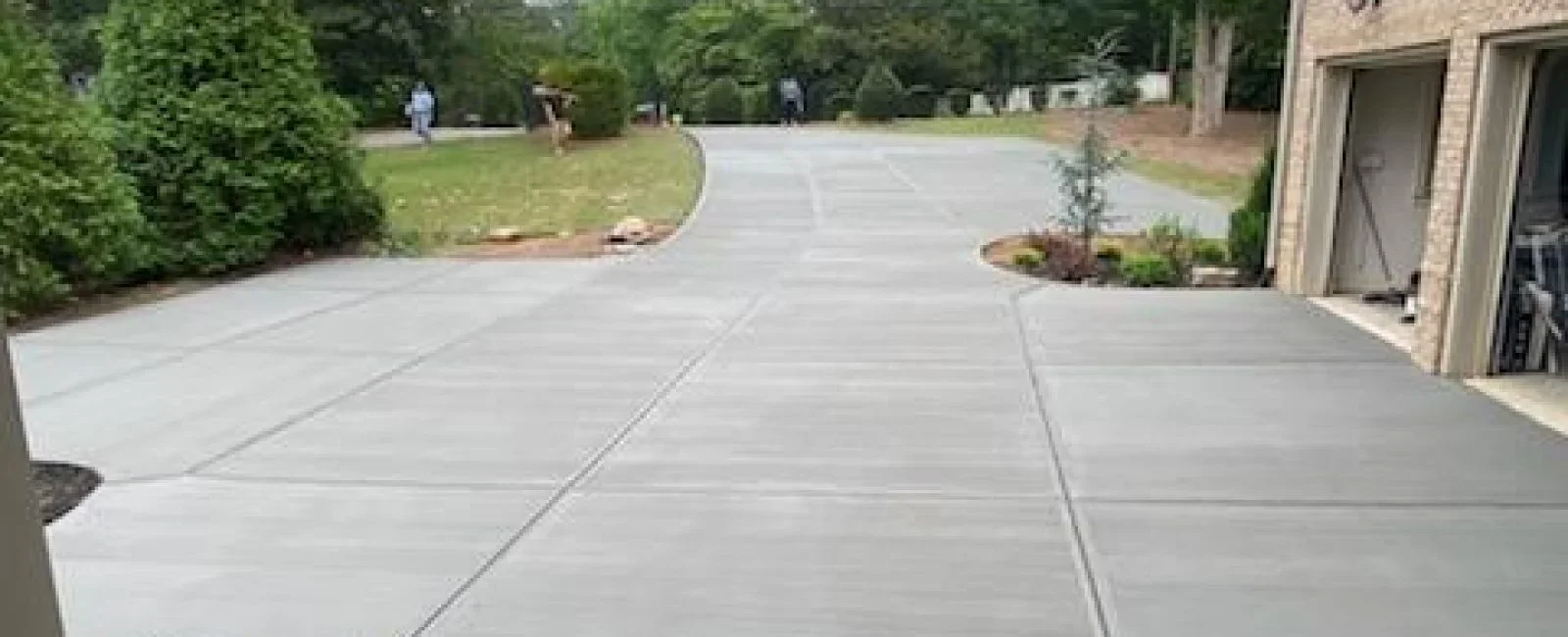 Newly poured concrete driveway with control joints leading to brick home entrance
