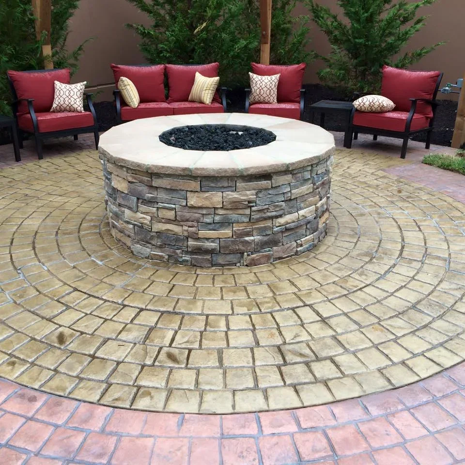 Circular paver patio with stacked stone fire pit, radial brick pattern, white cap, and black lava rock