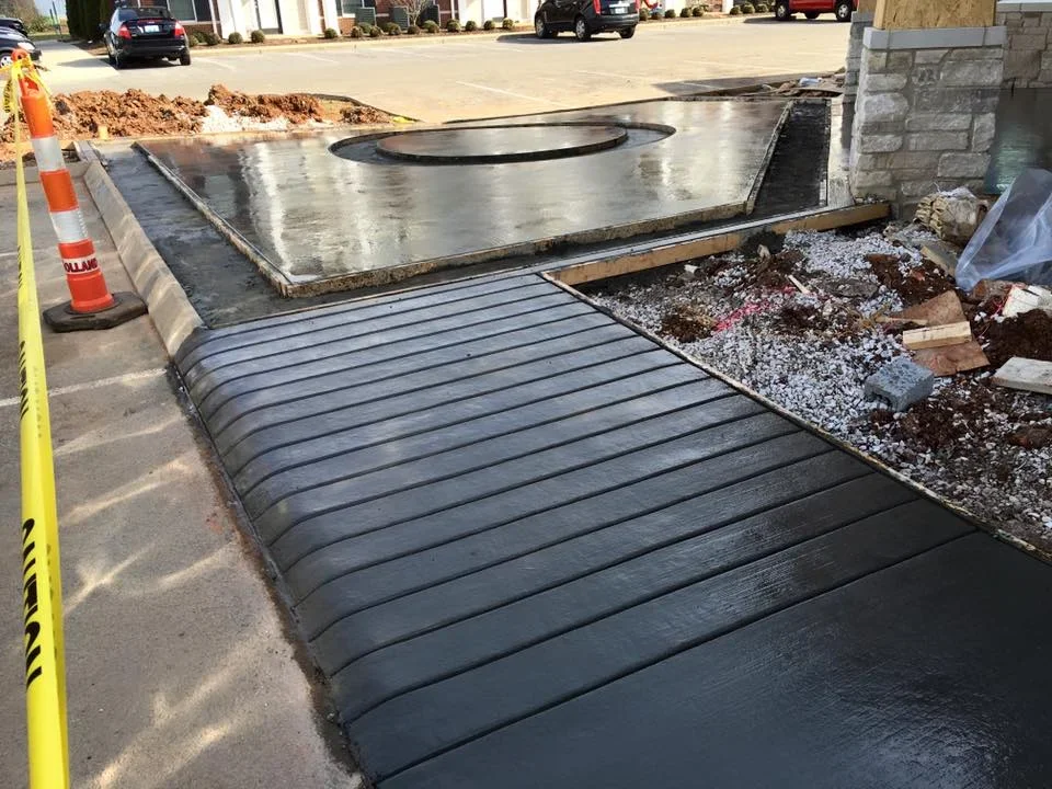Finished concrete pad with utility access opening and metal edging in commercial lot