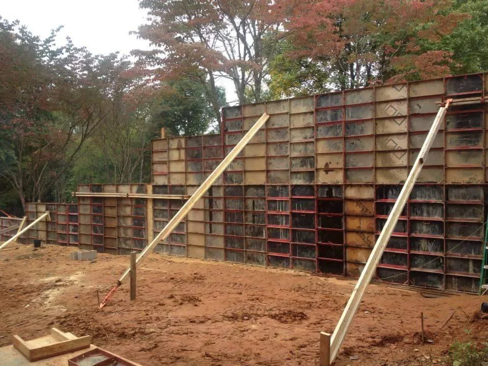 Metal livestock pen gates with wooden posts and concrete footings in rural setting