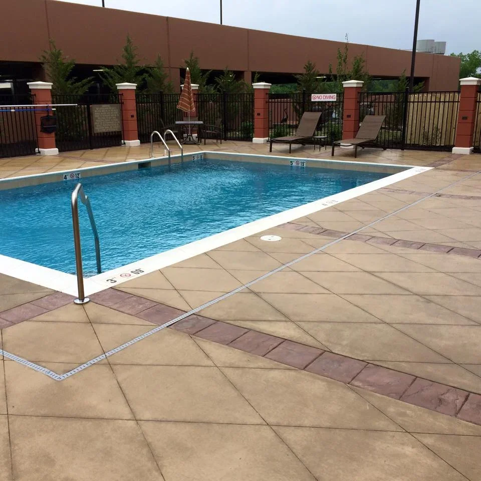 Stamped concrete pool deck with geometric pattern and depth markers surrounding blue swimming pool